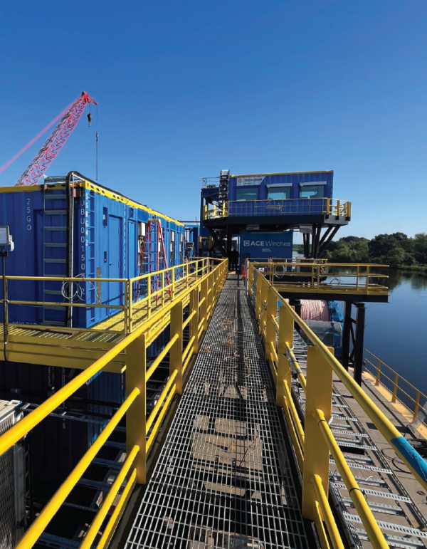 Modular offshore buildings mounted on a cable-lay barge with integrated access platforms and railings.