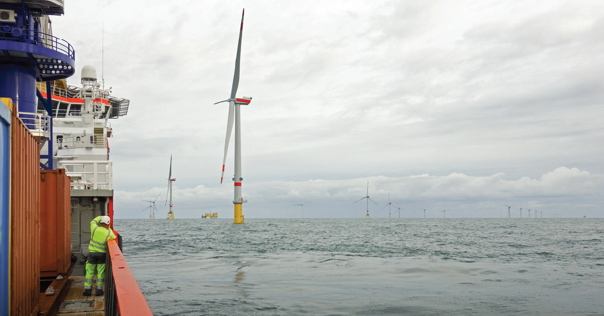 Crew member on the deck of an offshore support vessel overlooking an offshore wind farm during marine operations.