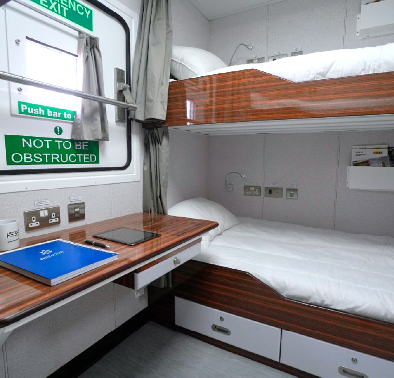 Offshore accommodation module with bunk beds, desk and emergency exit.