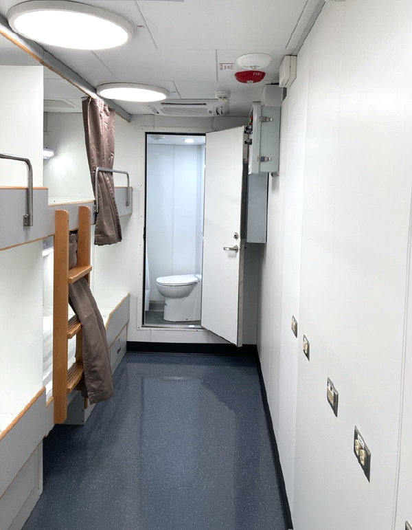 Compact ship cabin corridor with bunk beds and bathroom