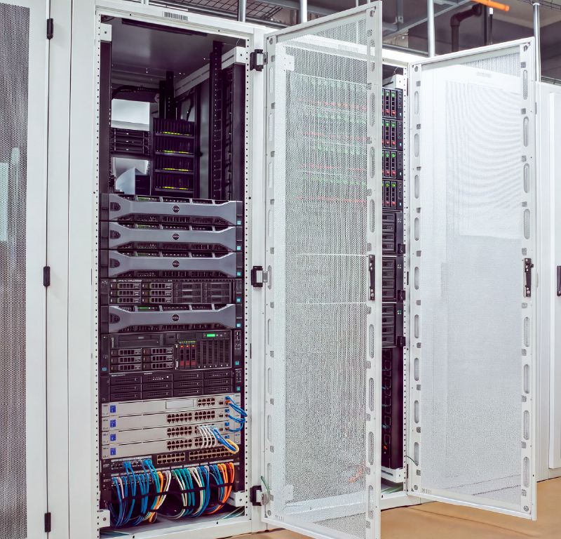 Open equipment racks containing servers, network switches, and organized cabling inside a technical equipment room.